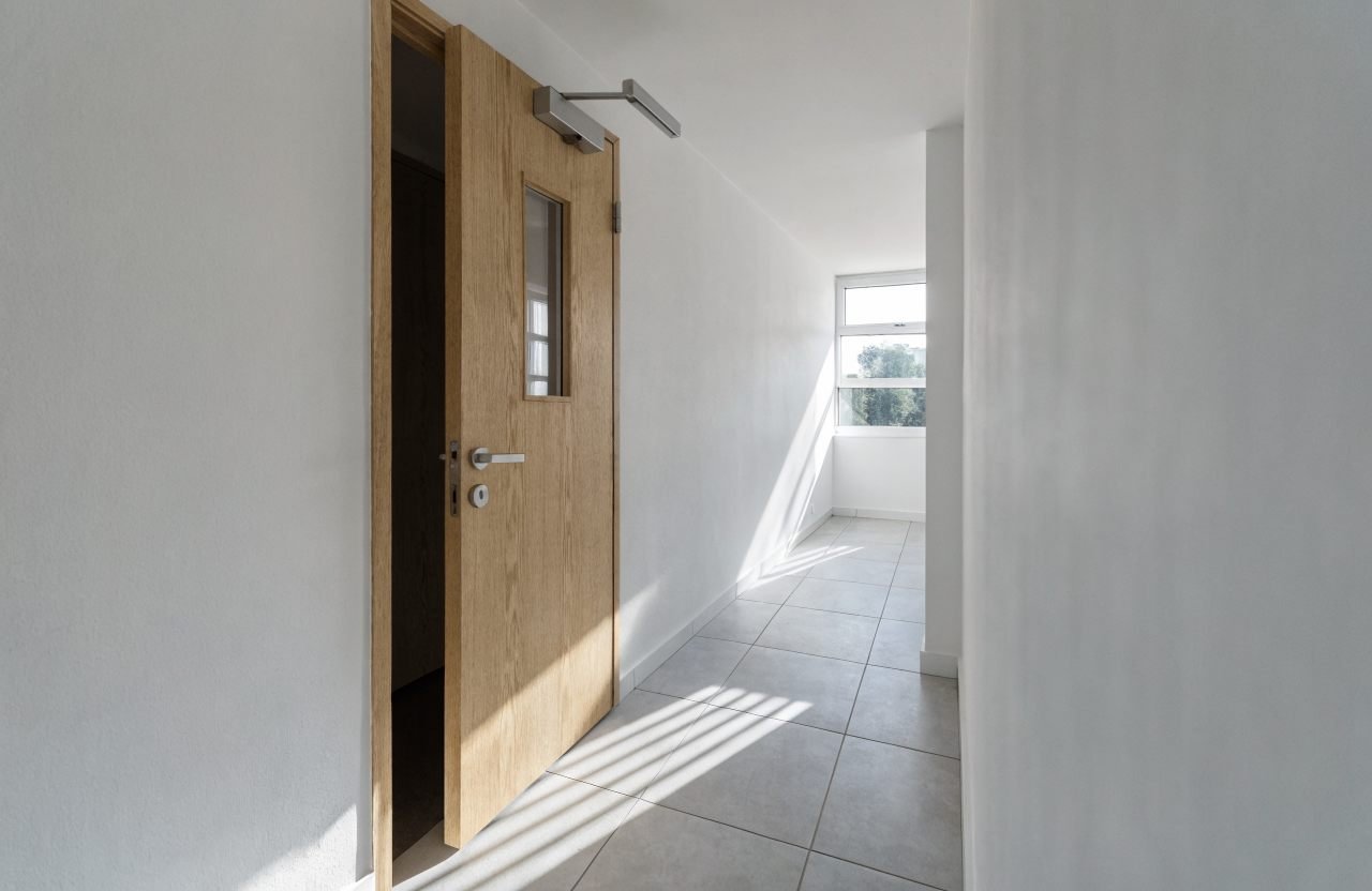 FD30 fire door with glazed vision panel in a London apartment block corridor
