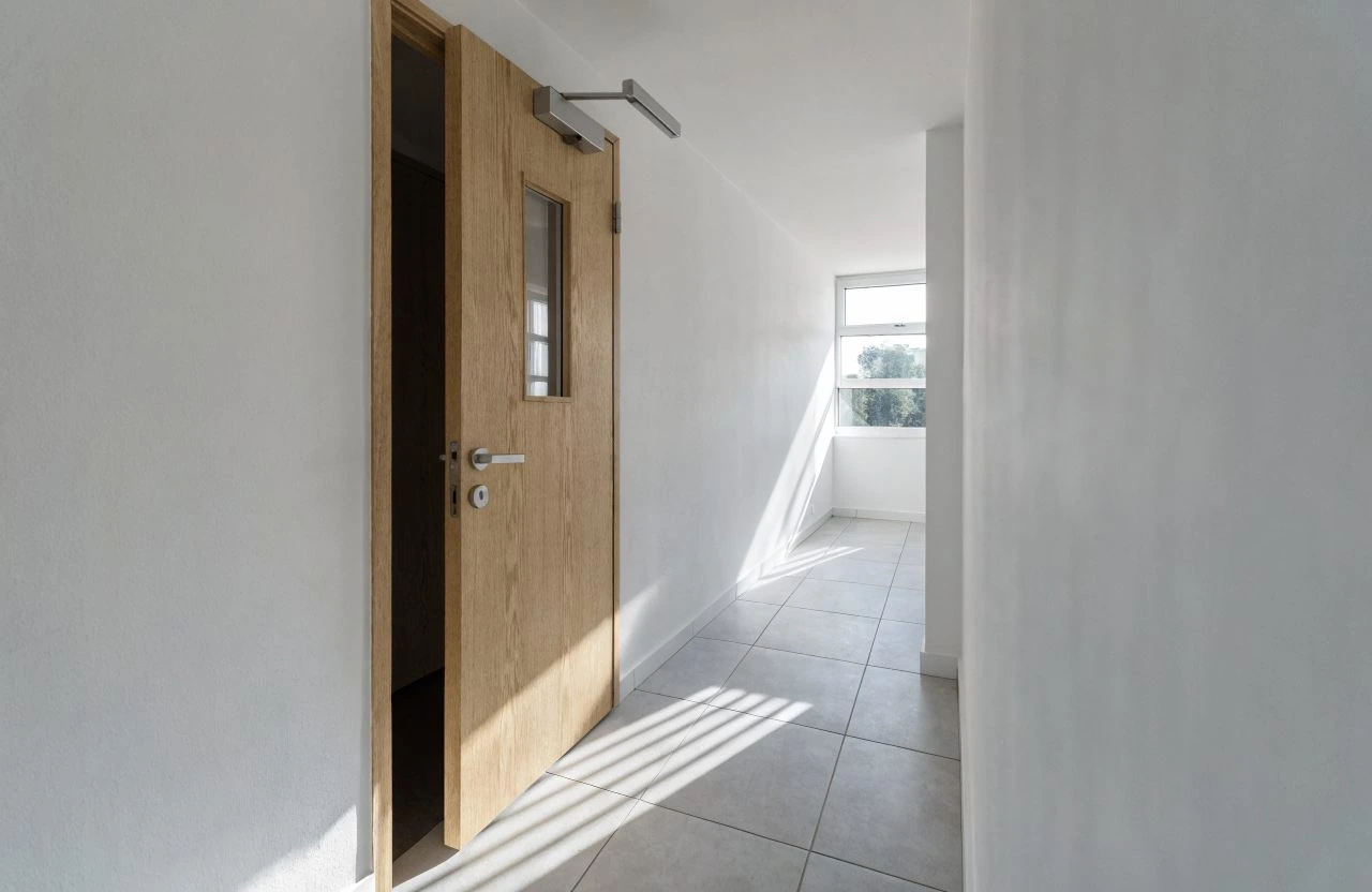 FD30 fire door with glazed vision panel in a London apartment block corridor