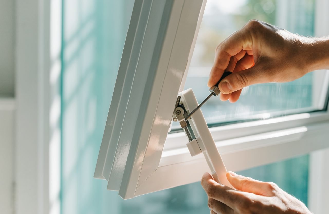 Window repair engineer adjusting a uPVC friction hinge in London
